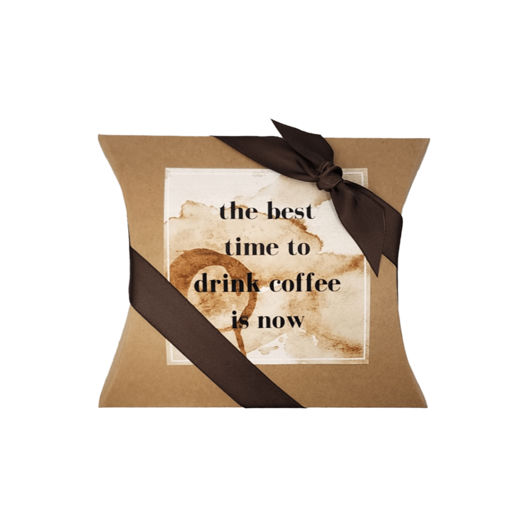 DRINK COFFEE NOW MINI COFFEE GIFT: A brown pillow box with a ribbon, containing churro cinnamon coffee, creamers, candies, and a personalized card.