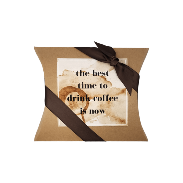 DRINK COFFEE NOW MINI COFFEE GIFT: A brown pillow box with a ribbon, containing churro cinnamon coffee, creamers, candies, and a personalized card.