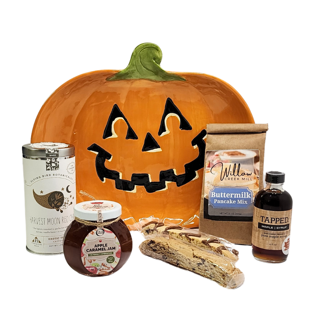 Pumpkin Patch Breakfast Gift featuring a jack o' lantern platter with pancake mix, maple syrup, chai tea, apple caramel jam, and biscotti.