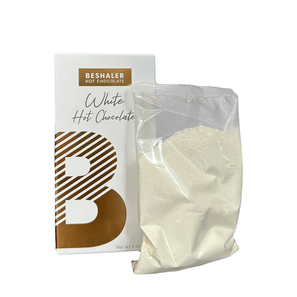 White Hot Chocolate in a bag beside a white and gold package, showcasing a creamy mix for indulgent cups of hot cocoa.